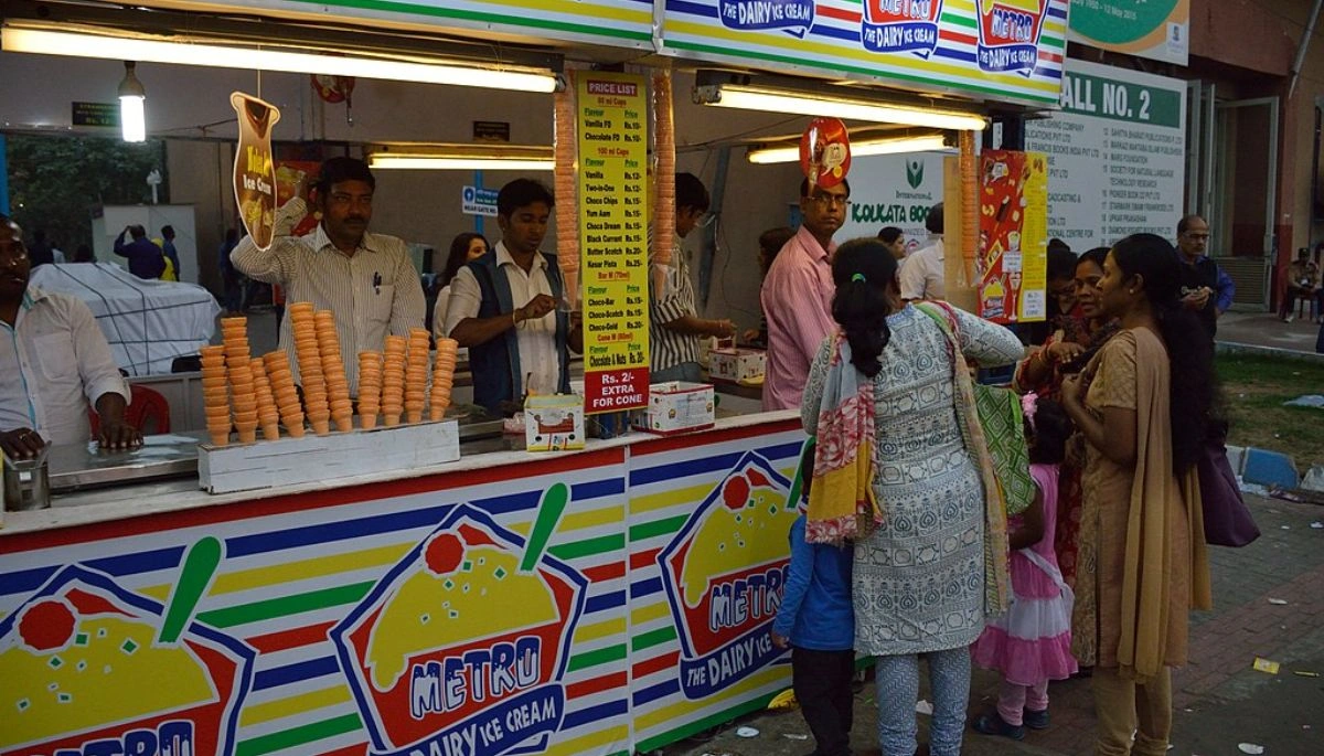 People enjoying ice cream at Mahayogini Mela in Saharsa, with unique serving style and music.