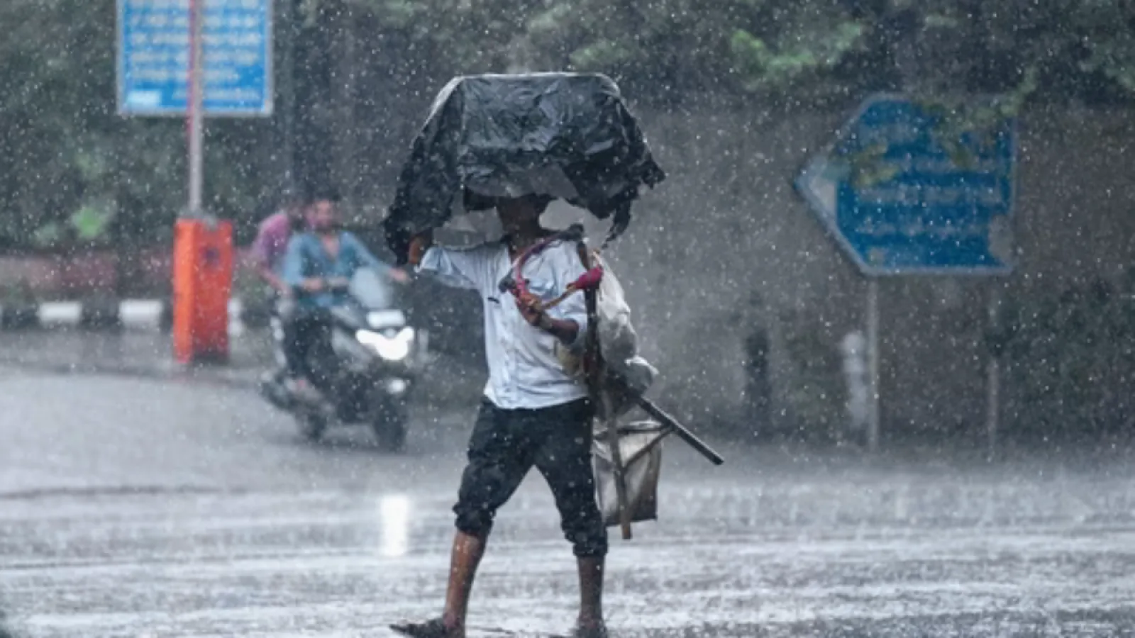 Delhi Weather: दिल्ली में मानसून की बारिश के बीच छतरी लिए चलते लोग, बादलों से ढका आसमान और हल्की फुहारें